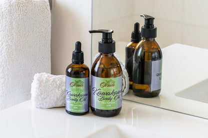 Oriwa Naturals kawakawa body oil moisturiser for sensitive skin in a 200ml pump top bottle and a 100ml dropper bottle, arranged with towels.